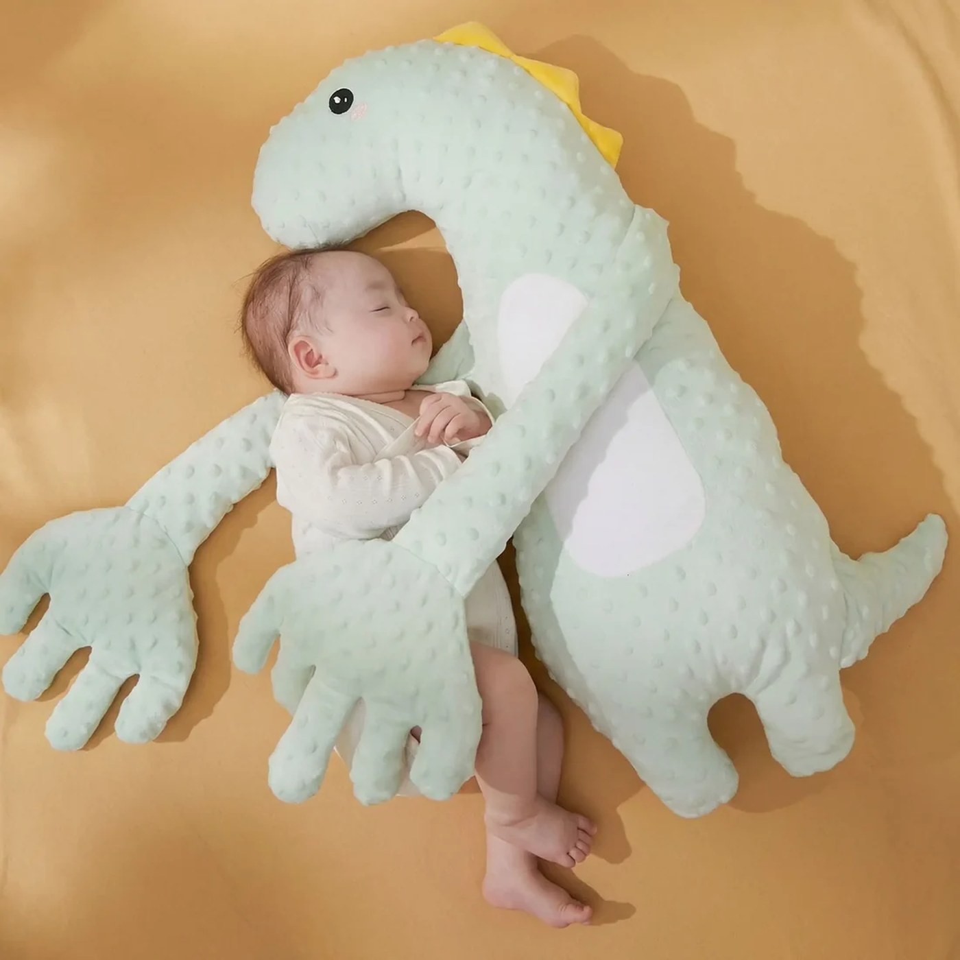 Un bébé endormi contre le doudou, les bras repliés